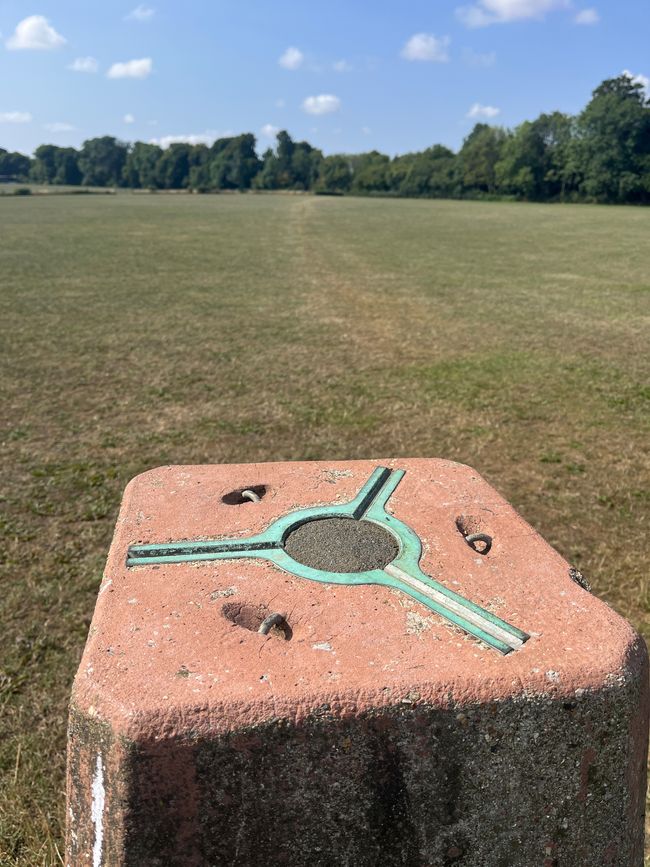 The top of an orange trig point in an empty field