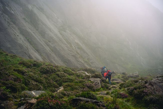 Mountains hidden by fog with people walking along a path