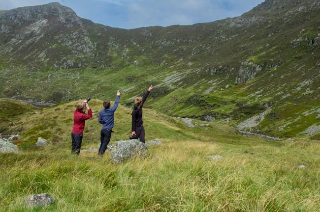3 men poinging up a mountain