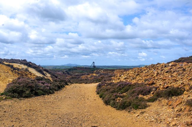 A orange gravel footpath with a mine in the background.