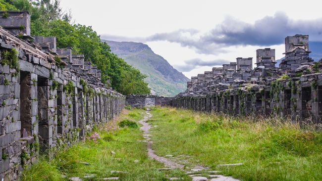 A footpath with a row of terraced cottage on either side that are in disrepair