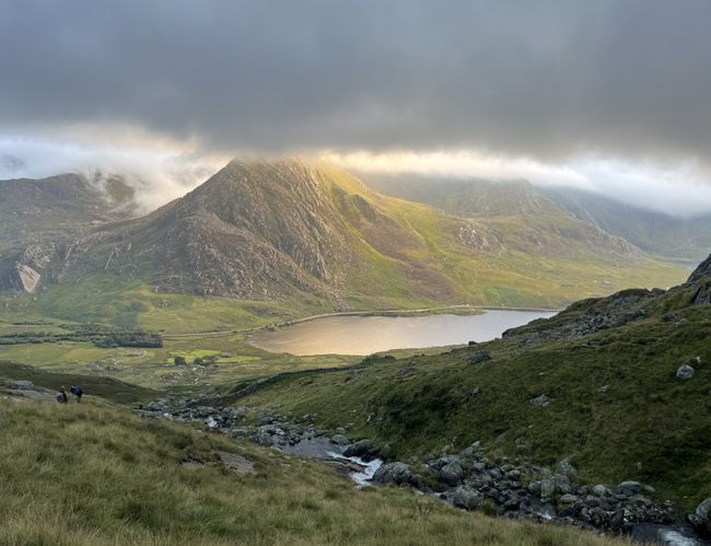 Some large moutains surrounded by cloud with the sun starting to poke through